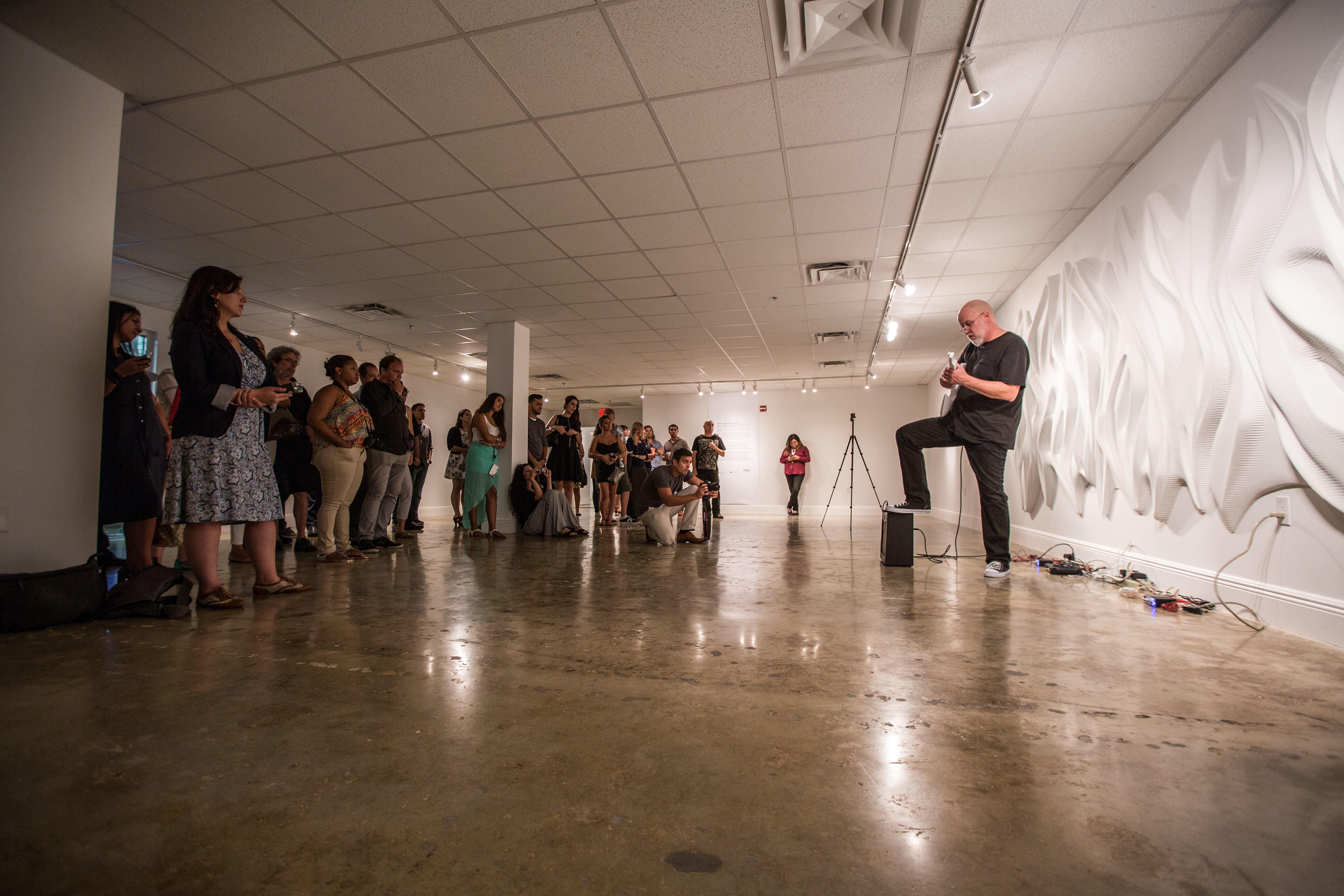 Performance space with standing audience and guitar-playing performer